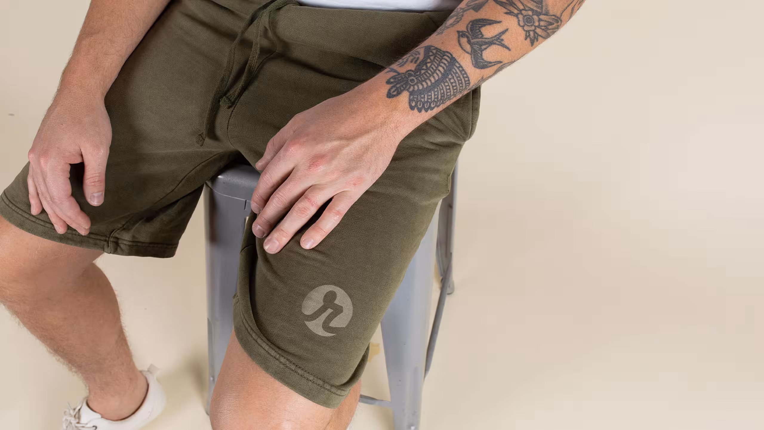 man sitting on a stool with olive shorts