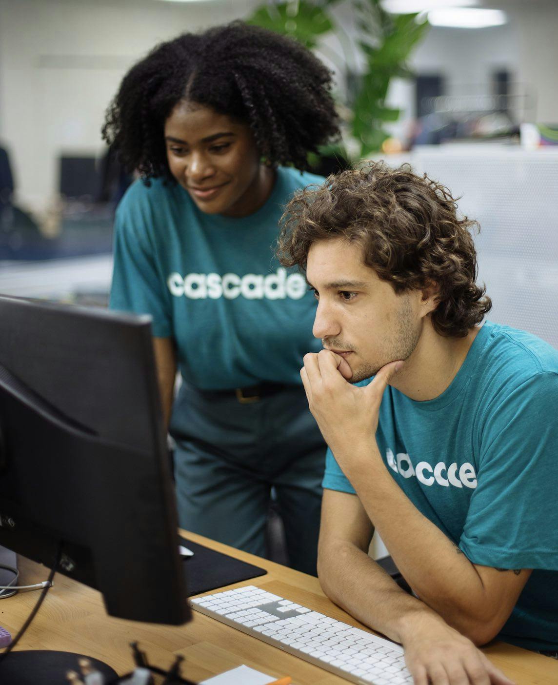 Two people wearing matching custom branded shirts work together at the computer. Two people wearing matching custom branded shirts work together at the computer.